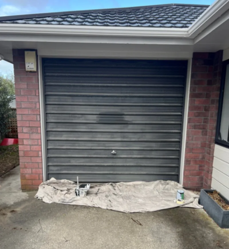 Garage roller door with an uneven dark finish before repainting.