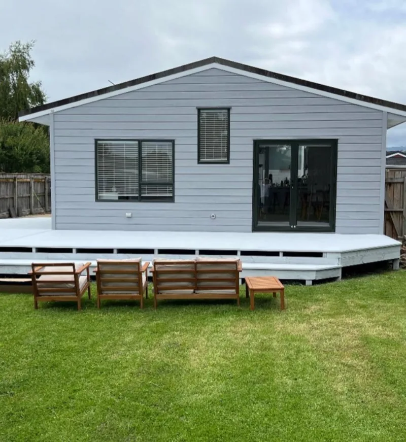 The weatherboard exterior and deck painted light grey and white.