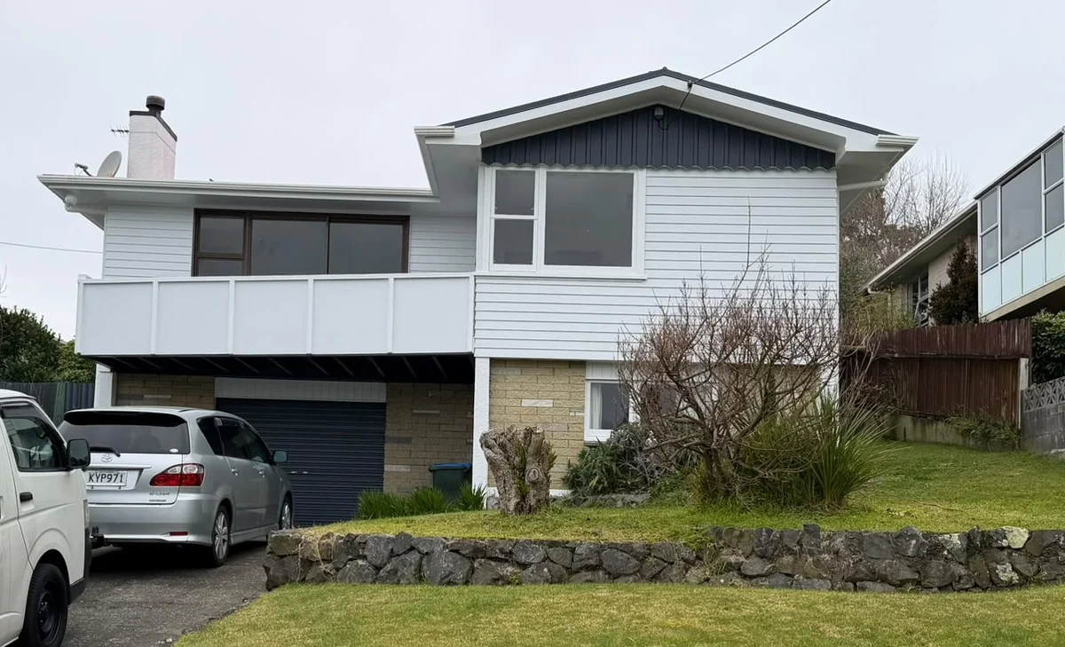 Two-storey weatherboard house with white cladding and dark trim.
