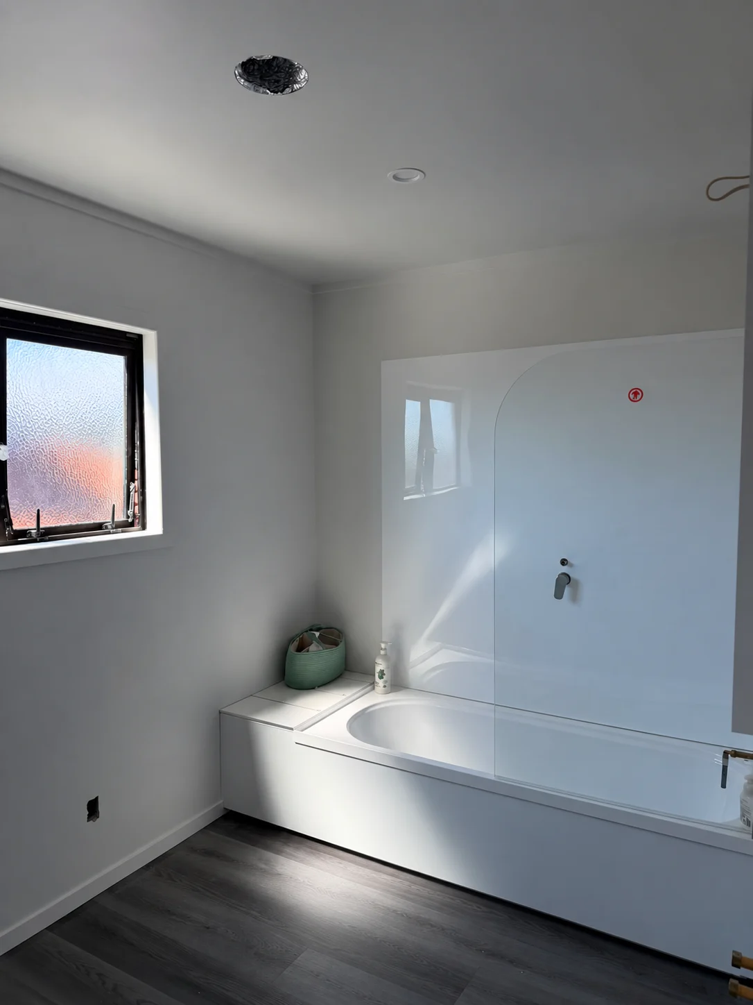 Light-painted bathroom walls beside a window and bath.